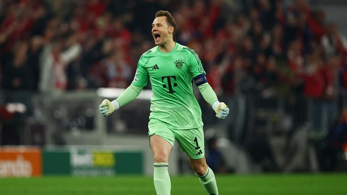 Bayern Munich goalkeeper Manuel Neuer celebrating on the pitch in a bright green kit with arms raised.