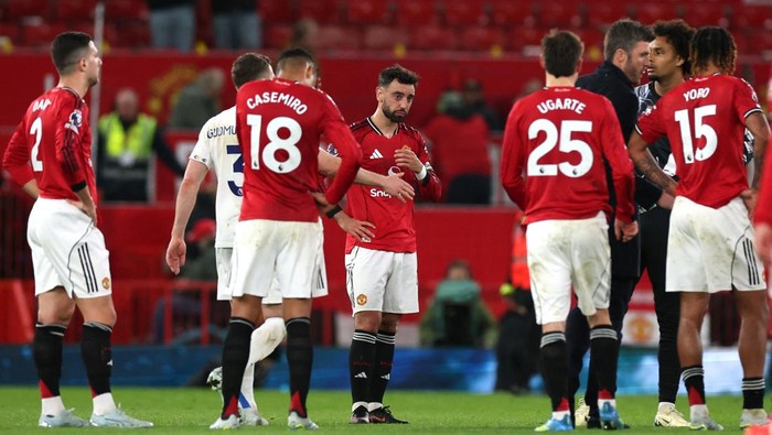 Manchester United players in red jerseys gather on the pitch during a break, with Casemiro 18, Ugarte 25, and Yoro 15 visible in the huddle.