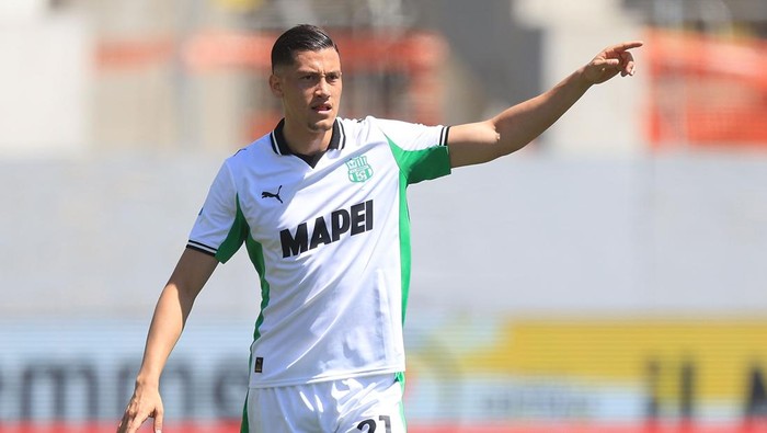 Soccer player in white and green kit pointing to his left during a match on the field.