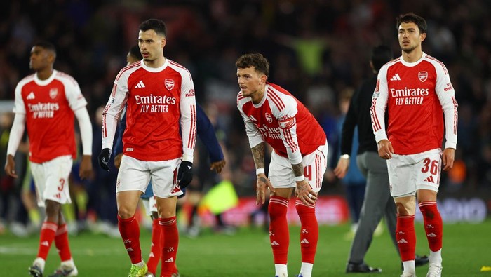 Group of Arsenal soccer players in red and white jerseys standing on a pitch during a match, looking ahead with focused expressions