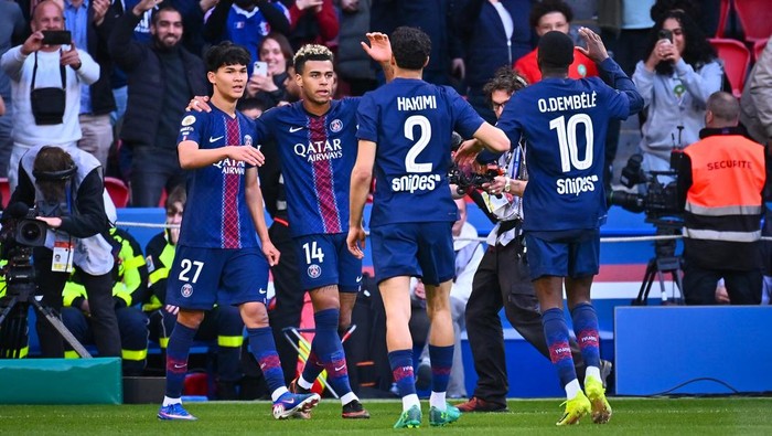Paris Saint-Germain players celebrate on the field, arms around each other after a play, in blue kits with Qatar Airways logos.