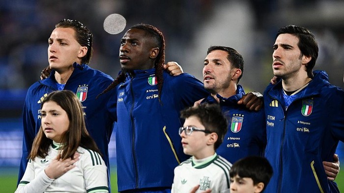 Italy national football team players with two children in front, standing with arms over each other’s shoulders before a match.