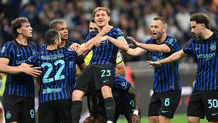 Inter Milan players celebrate a goal, lifting a teammate in blue-and-black striped kits on the field.