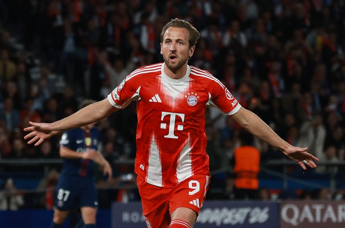 Bayern Munich forward in red kit with number 9, arms spread, celebrating on the pitch after a goal