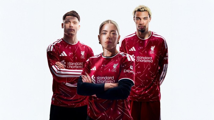 Three people wearing red Liverpool FC jerseys stand together with serious expressions, arms crossed in a promo photo.