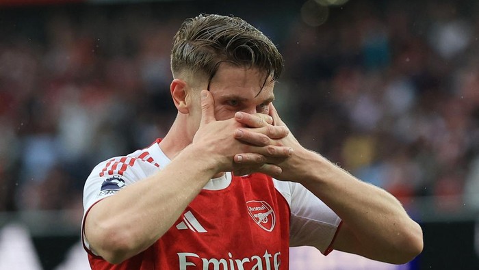 Arsenal soccer player in a red-and-white jersey covering his mouth with his hands during a match.