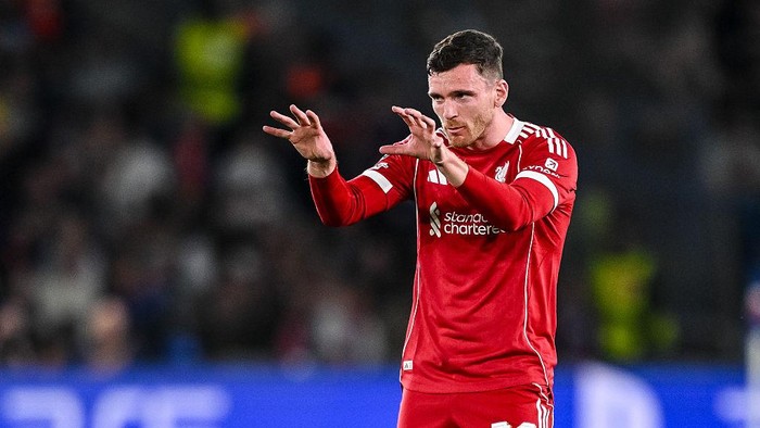 Liverpool footballer in red kit signaling with hands during a match on the field