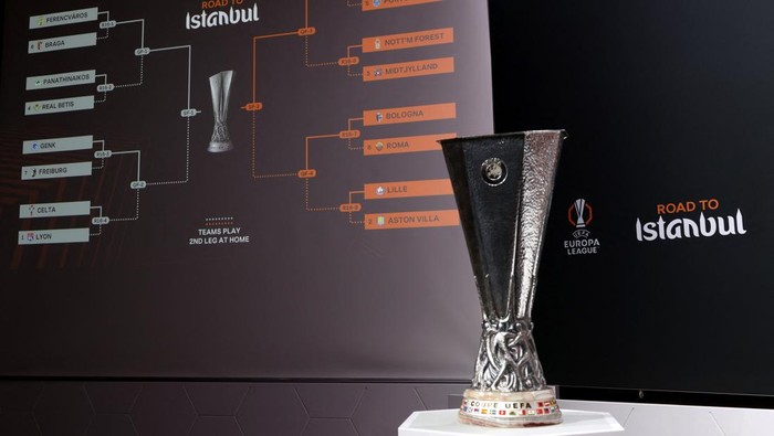 UEFA Europa League trophy on a pedestal with a large bracket diagram behind it labeled 'Road to Istanbul' and team names.