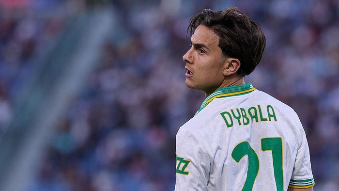 Soccer player wearing a white jersey with green trim, back facing camera, number 21 and the name on the jersey visible, in a stadium crowd.