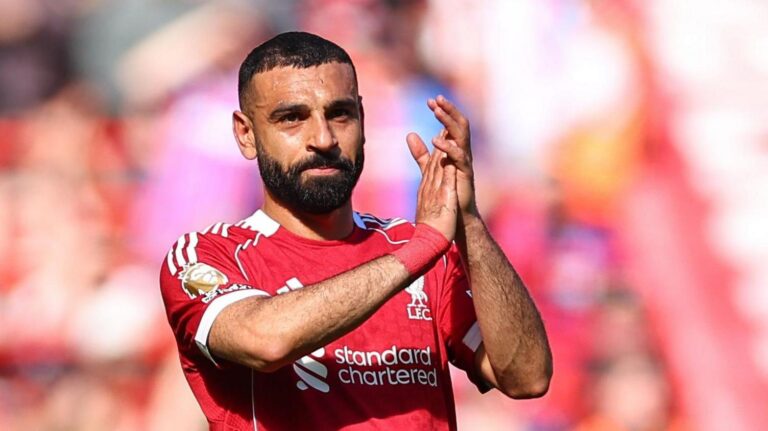 Bearded footballer in a red Liverpool jersey clapping on the pitch during a match
