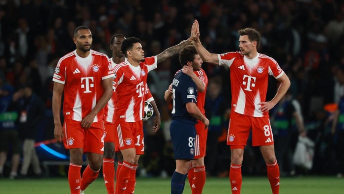 Bayern Munich players in red jerseys high-fiving on the field after a match.