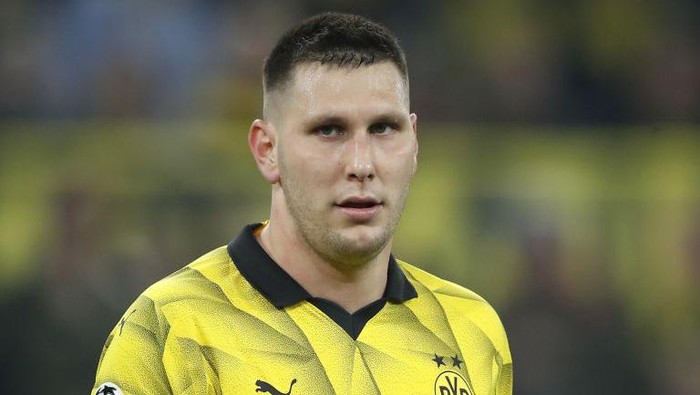 Close-up of a male soccer player wearing a yellow Borussia Dortmund jersey on the pitch, looking ahead.
