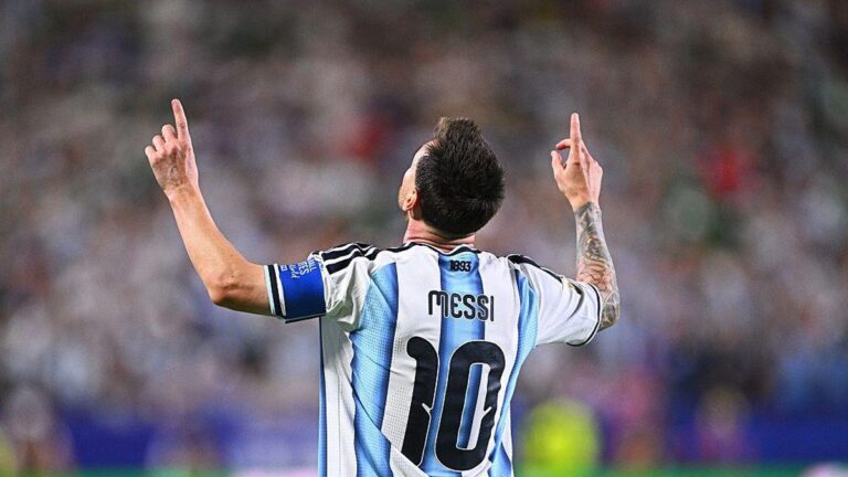 Soccer player in Argentina jersey with number 10 raises arms in celebration from back view.