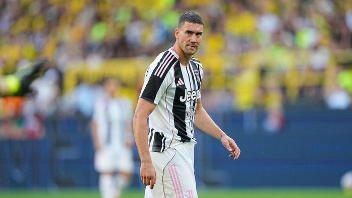 Soccer player in a black-and-white Juventus jersey on the field, looking toward the camera.