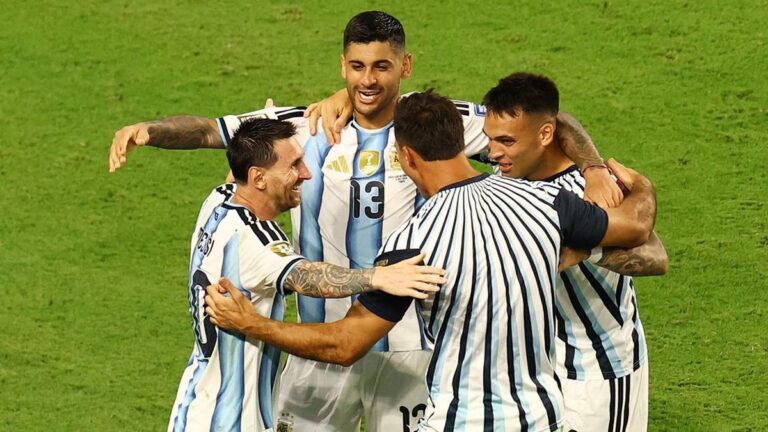 Argentina national team players celebrate with a group hug on the soccer field.