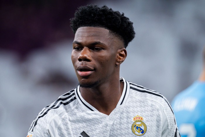 Soccer player in Real Madrid white jersey on the field, looking ahead with a focused expression.