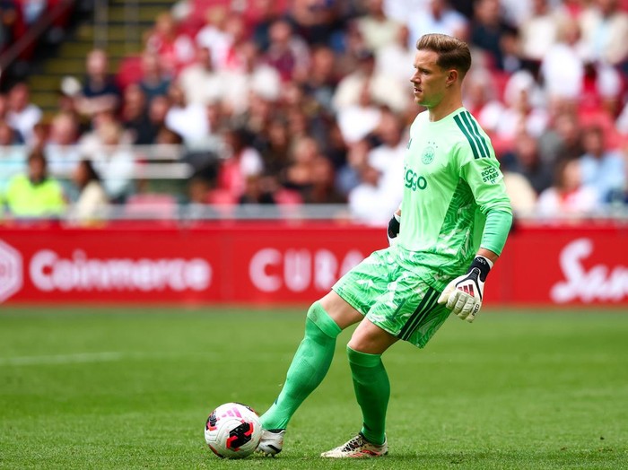 Soccer goalkeeper in bright green uniform controls the ball on the field during a match.