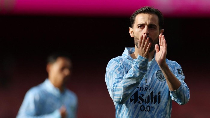 Cricketer in a light blue jersey celebrating, clapping on the field.