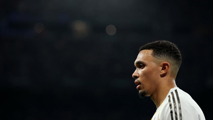 Profile view of a male footballer in a white kit, looking to the right against a dark background.