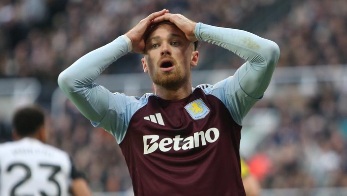 Soccer player in a maroon jersey with hands on head, looking disappointed during a match.
