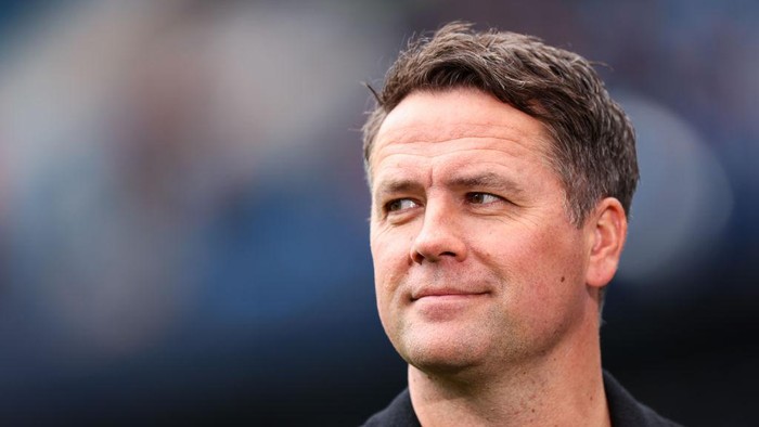 Close-up portrait of a middle-aged man with short brown hair, looking to the right, neutral expression, blurred outdoor background