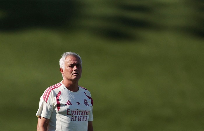 Man in a Real Madrid jersey standing on a grassy field, looking off to the side during practice or a game.