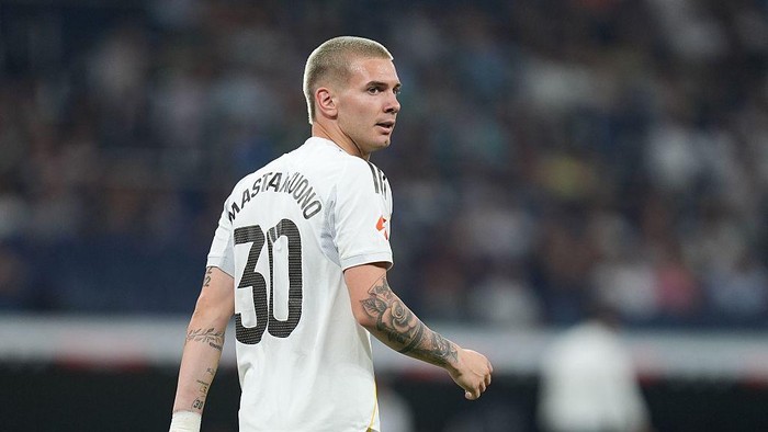 Soccer player in a white jersey with number 30 on the back, turning toward the camera with a tattooed arm visible.