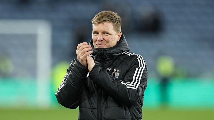 Soccer coach in a black puffer jacket clapping on the sidelines.