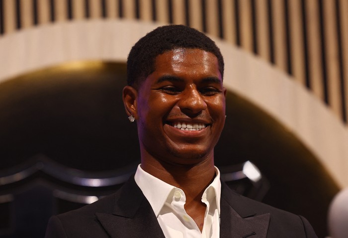 Smiling man in a dark suit and white shirt at a formal event, smiling at the camera.