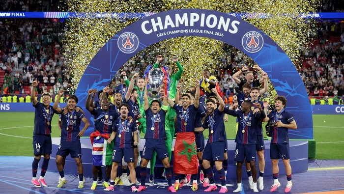 PSG players celebrate winning the UEFA Champions League Final 2026, lifting the trophy under a blue arch with confetti falling.