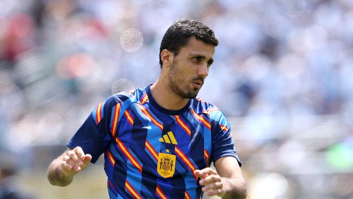 Soccer player in a blue striped Spain jersey jogging on the field, focused on the game