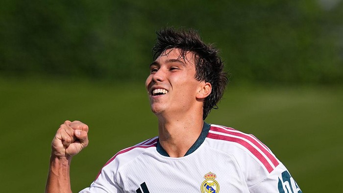 Soccer player in a Real Madrid jersey celebrating with a raised fist on a green field.