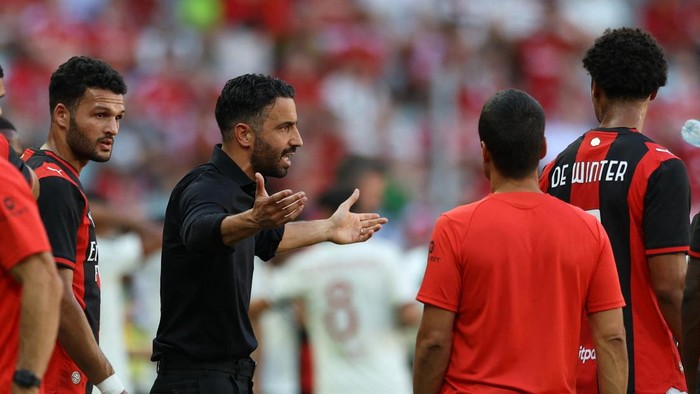 Soccer coach gesturing angrily at players during a discussion on the field.