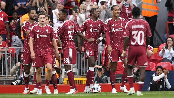 Liverpool FC players in maroon kit standing on the pitch during a match or celebration.