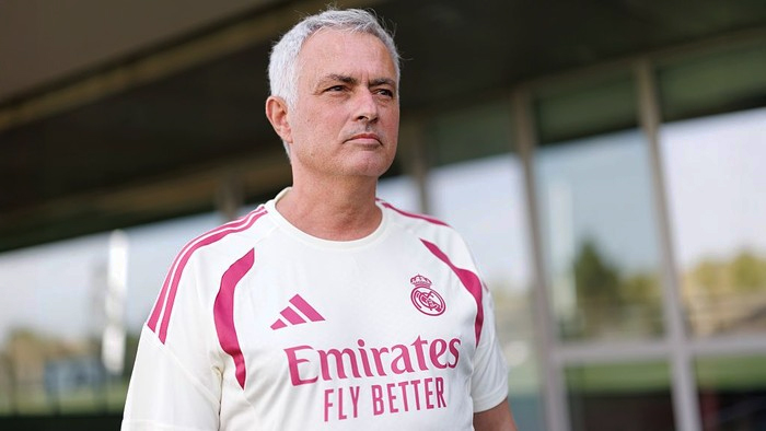 Portrait of a man with short gray hair wearing a Real Madrid jersey outdoors, looking ahead with a serious expression.