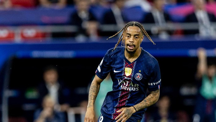Paris Saint-Germain soccer player with braided hair runs on the field during a match.
