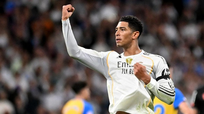 Cristiano Ronaldo in a Real Madrid kit pumps his fist in celebration on the pitch.