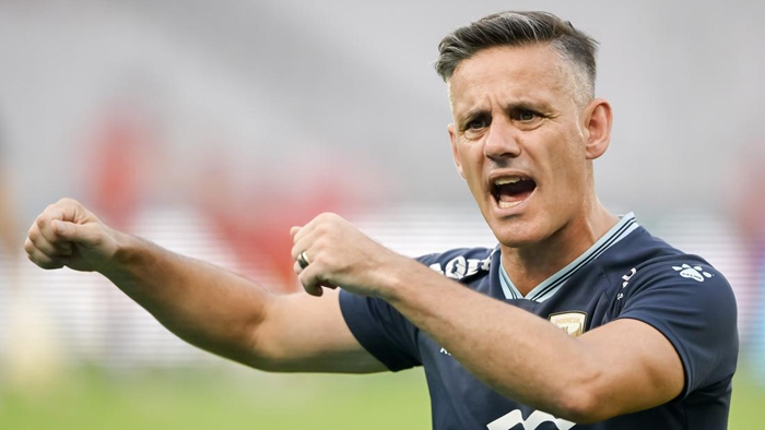 Male soccer player shouts with fists raised, shouting to teammates on the field.