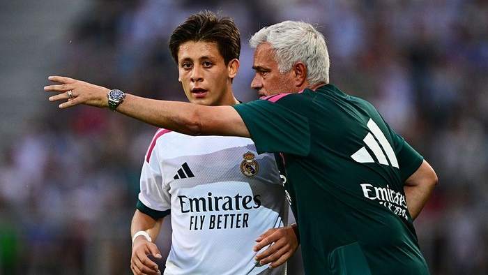 Real Madrid coach Carlo Ancelotti points and talks to midfielder James Rodríguez during a match on the field.