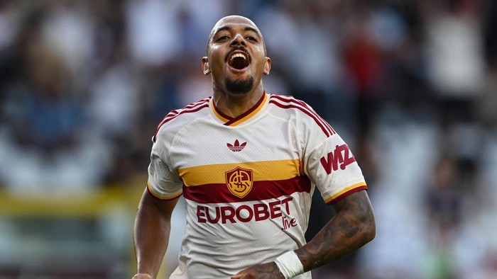 Soccer player in AS Roma white jersey celebrating a goal with mouth open and arms outstretched.