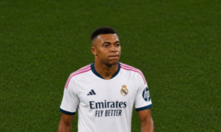 Real Madrid football player in a white kit with Emirates sponsor on green pitch.